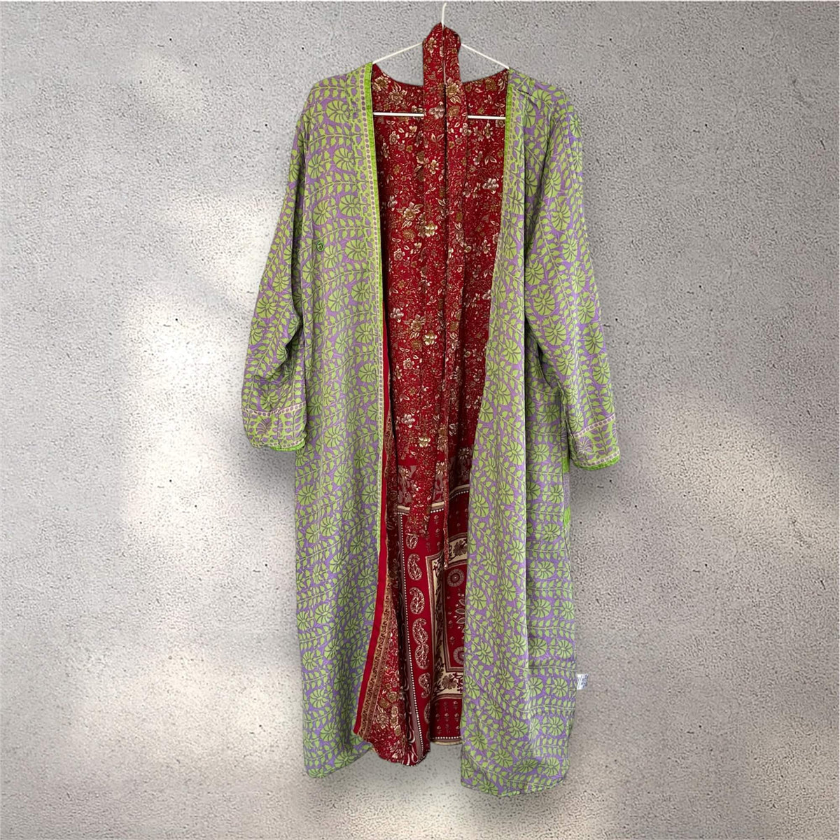 Grøn og rød kimono med mønster, hængende på en væg.