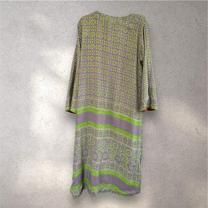 Kimono i lilla og grøn mønster hænger på en grå væg.