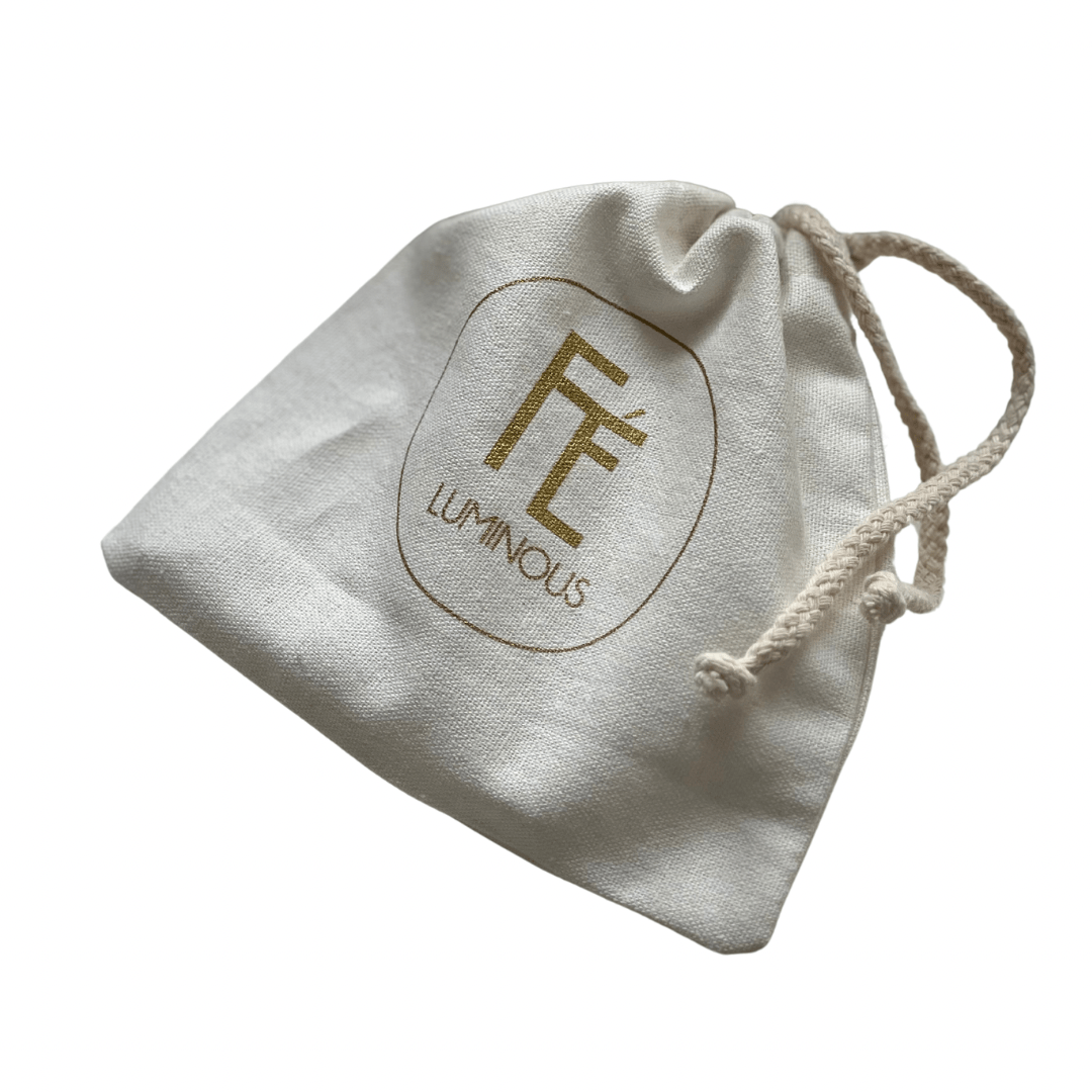 Hvid stofpose med logoet "FÉ Luminous", brugt til FÉ Selenit plade.