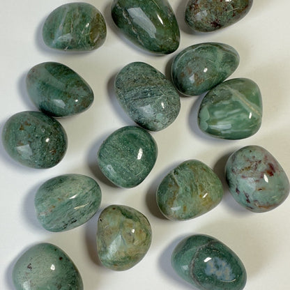 Chrysocolla grønne lommesten på hvid baggrund, poleret og placeret tilfældigt.