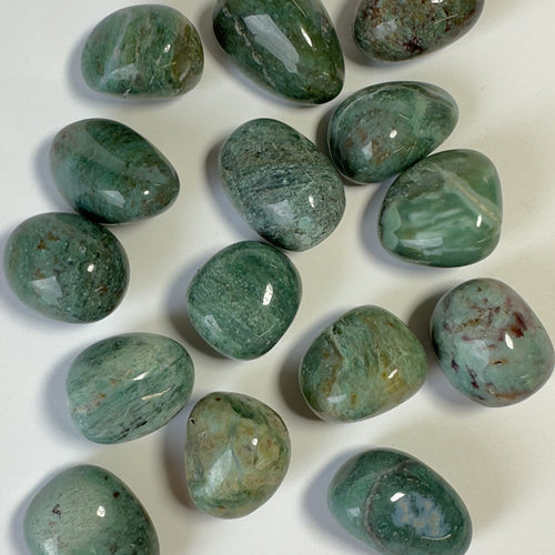 Chrysocolla grønne lommesten på hvid baggrund, poleret og placeret tilfældigt.