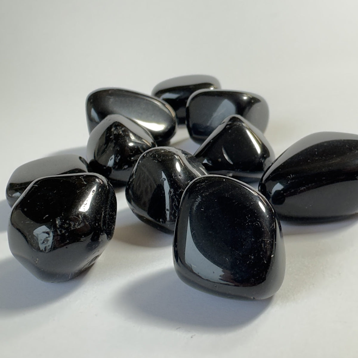Sort obsidian-sten lagt på en hvid overflade, skinnende og polerede.