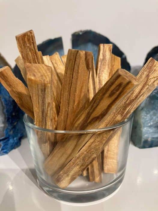 Glas med Palo Santo-stykker, omkranset af blå sten.